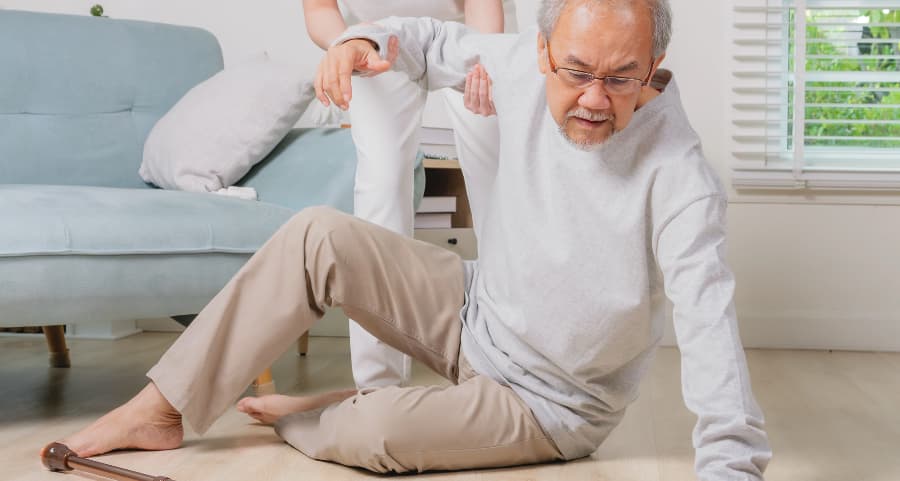 A senior getting helped up from the floor